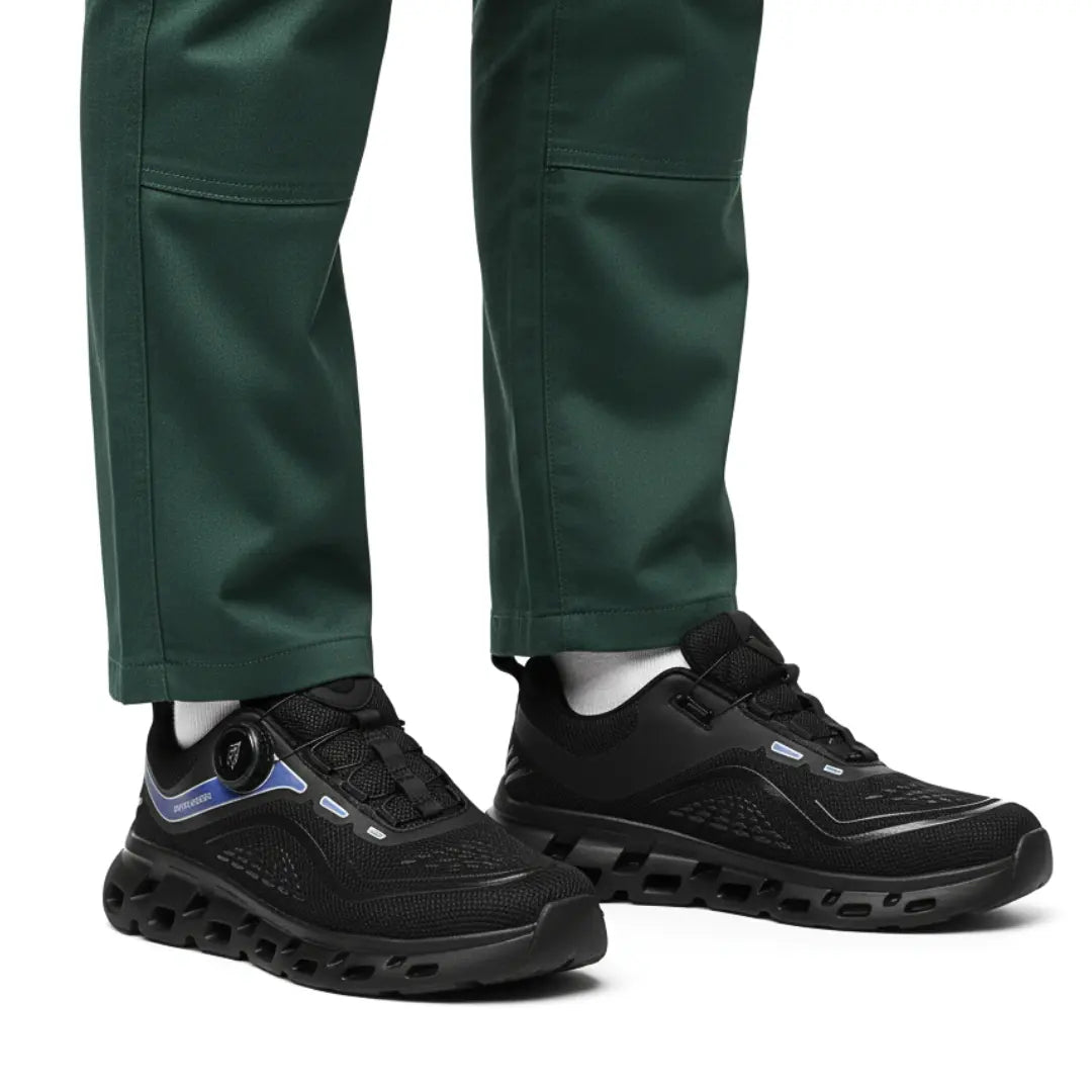 RewanPro GripX czarne buty robocze na stopie pracownika w zielonych spodniach